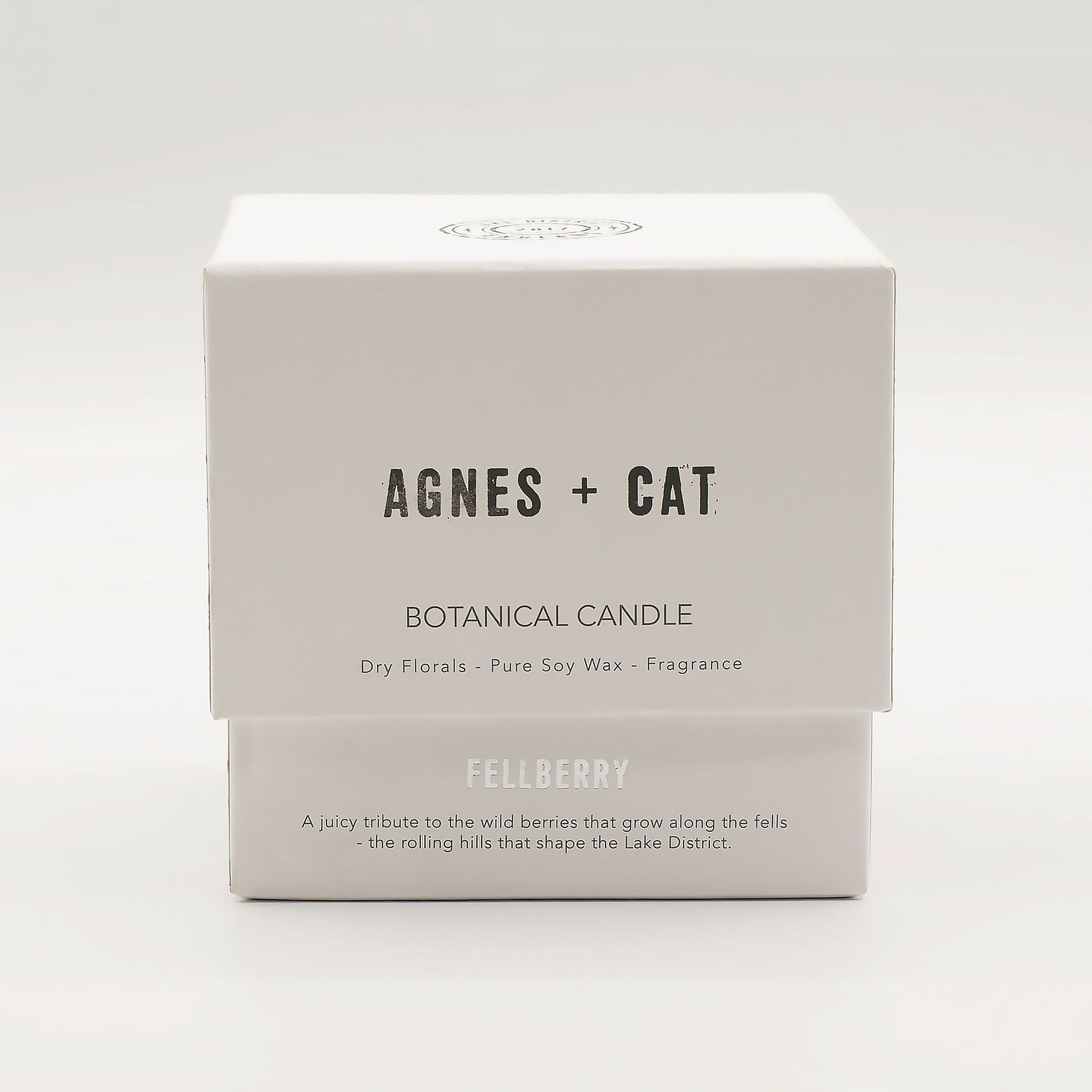 Agnes + Cat Fellberry botanical soy wax candle in a clear glass vessel with a wooden wick and dried floral petals