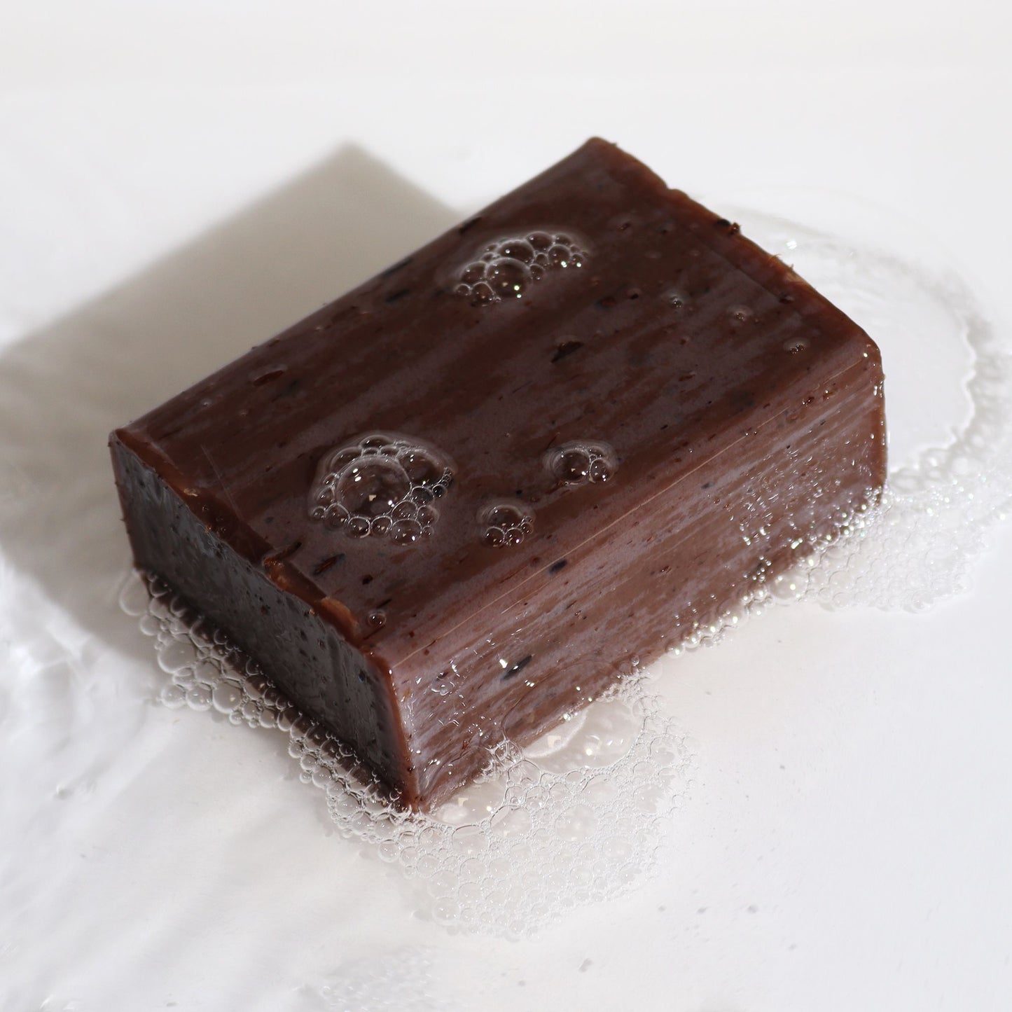 Artisan Lavender & Vanilla botanical soap block with natural lavender seeds.