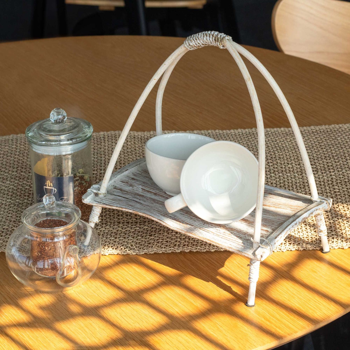 Handcrafted whitewashed coconut leaf and rattan tea stand for displaying teaware.