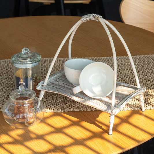 Handcrafted whitewashed coconut leaf and rattan tea stand for displaying teaware.